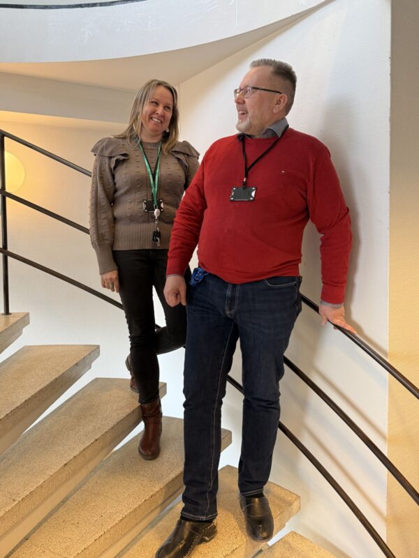 Salon työllisyyspalveluiden johtava omavalmentaja ja työllisyysasiantuntija seisomassa portaikoissa. He katsovat toisiaan ja hymyilevät.